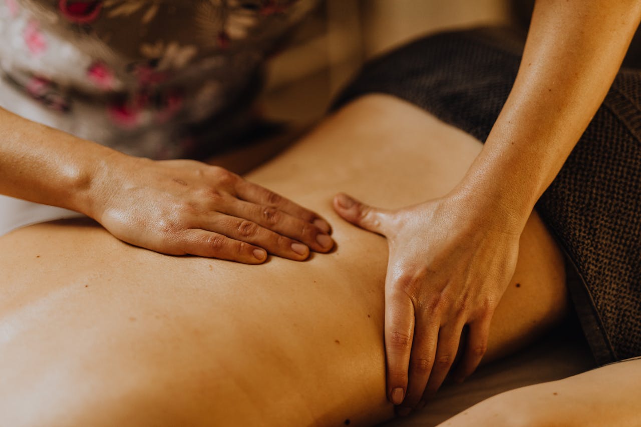 A Close-Up Shot of a Masseues Massaging a Person's Back